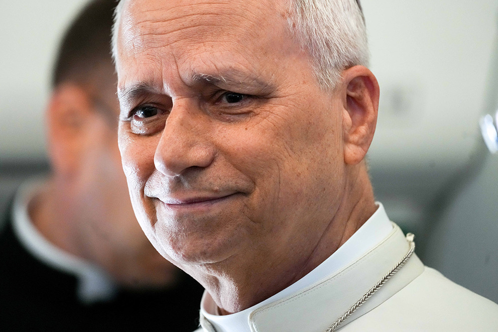 Close-up of a smiling man in a white clerical collar, looking at the camera.